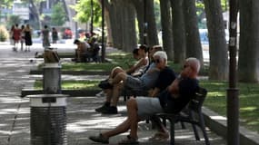Des personnes assises à l'ombre dans un parc pendant une vague de chaleur, le 17 juin 2022 à Perpignan, dans les Pyrénées-Orientales