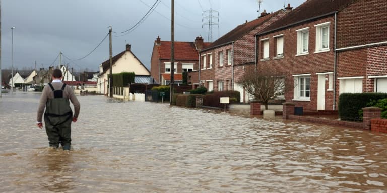 Un homme marche le 3 janvier 2024 dans une rue inondée d'Arques, dans le nord de la France, suite à la crue de l'Aa