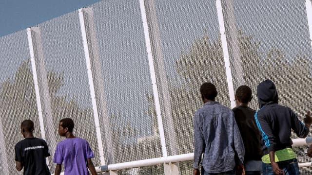 Des migrants marchent à côté d'une clôture bordant la Jungle, à Calais, le 8 septembre 2016.