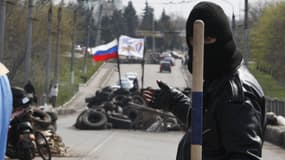 Un activiste pro-russe accompli un geste menaçant alors qu'il garde un barricade à Slaviansk dans l'est de l'Ukraine, le 14 avril 2014.