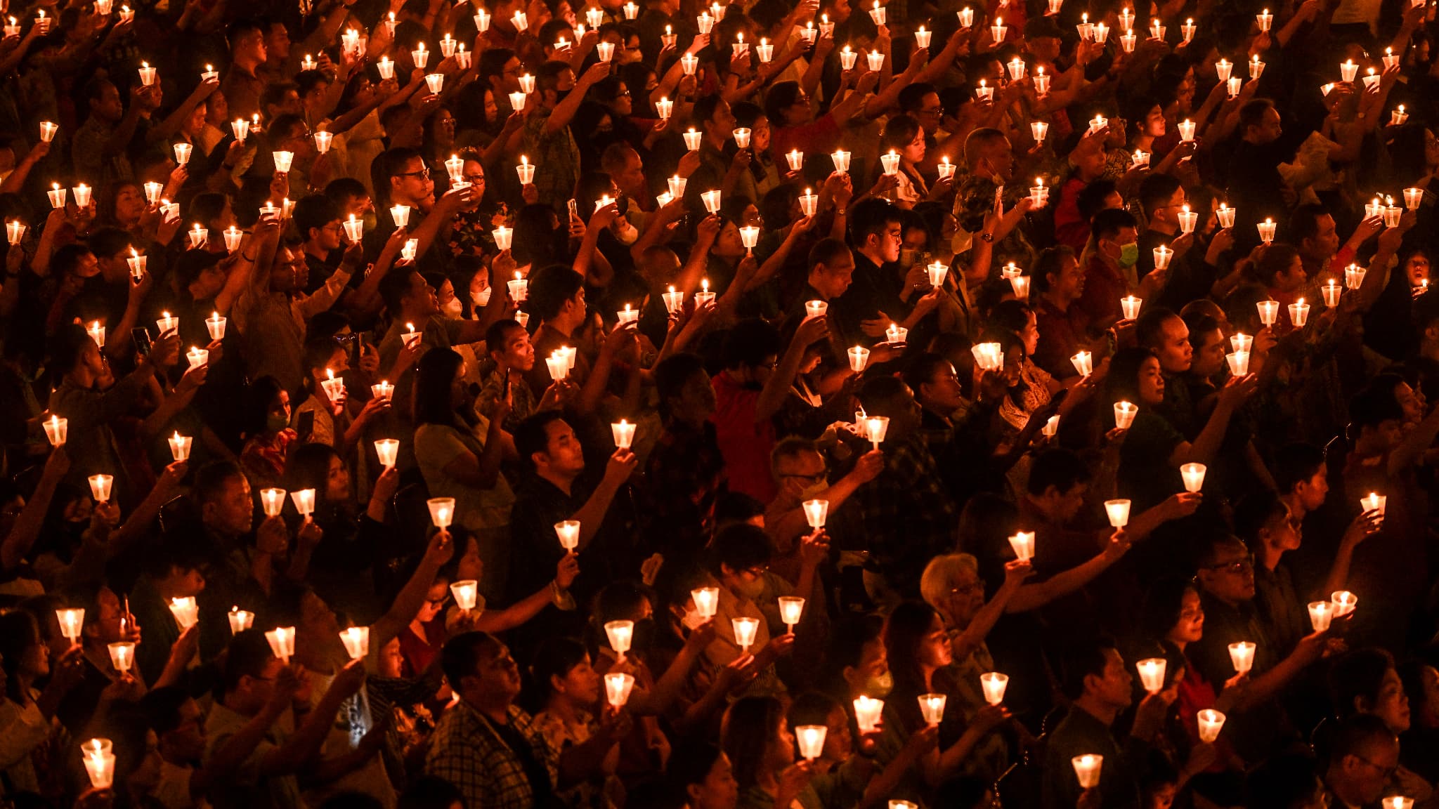 Des fidèles chrétiens tiennent des bougies pendant la messe de minuit de la veille de Noël à l'église Bethany de Surabaya, en Indonésie, le 24 décembre 2023.