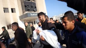 Un parent porte le corps d'un enfant tué dans une frappe israélienne qui a touché le nord de Khan Yunis dans le sud de la bande de Gaza, le 18 janvier 2025