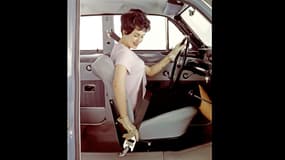 Une conductrice bouclant sa ceinture 3 points dans sa Volvo Amazon, une 122 dont la commercialisation a débuté en 1958.
