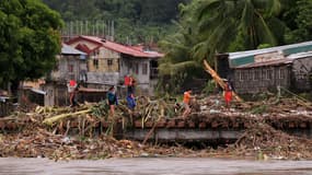 Des habitants traversent un pont rempli de débris en raison des fortes pluies provoquées par la tempête tropicale Trami dans la ville de Polangui, province d'Albay au sud de Manille, le 23 octobre 2024. 