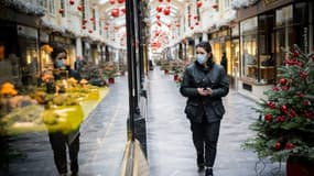Une femme portant un masque de protection congtre le Covid-19 marche dans Burlington Arcade, aux vitrines décorées pour Noël, dans le centre de Londres, le 23 novembre 2020
