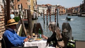 Des touristes attablés à une terrasse d'un restaurant à Venise, le 21 mai 2021 