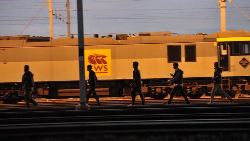 Des migrants longeant les rails du site Eurotunnel près de Calais