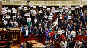 Les députés de gauche brandissent des affiches où sont inscrites la devise de la République française, le 19 décembre 2023 à l'Assemblée nationale