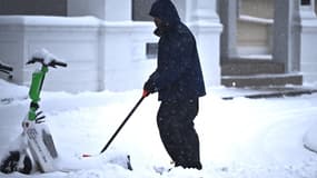 Un Américain déneige une rue enneigée de Washington, janvier 2025