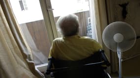 Une personne âgée se repose avec à ses côtés un ventilateur installé devant la fenêtre de son domicile à Paris, le 20 juillet 2006.