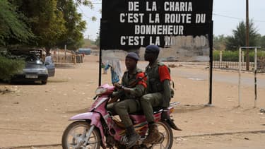 Soldats maliens circulant devant un panneau exaltant la Charia, en 2013.