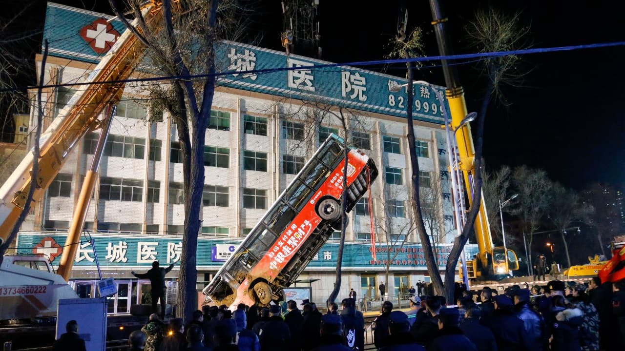Les équipes de secours chinoises remontent le bus qui a été presque englouti par un trou dans la chaussée, le 13 janvier 2020 à Xining, en Chine