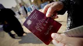 Une femme syrienne tenant son passeport à la main.