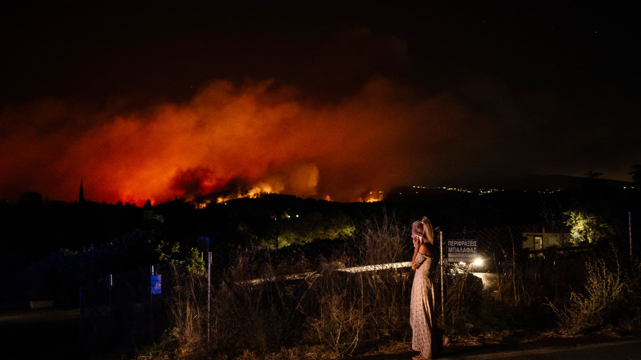 Des habitants regardant la progression des flammes à Varnavas, au nord d'Athènes, le dimanche 11 août 2024.