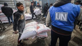 Un habitant de Rafah réceptionne des sacs de nourriture distribués par l'Unrwa aux côtés d'un employé de l'ONU, le 28 janvier 2024