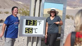 Deux touristes se prennent en photo à côté d'un relevé de chaleur non officiel pendant une vague de chaleur dans le parc national de la vallée de la Mort, en Californie, le 16 juillet 2023.