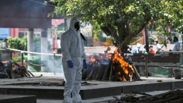 Vêtu d'une combinaison de protection, un proche d'une personne décédée du coronavirus se recueille durant la crémation, le 3 juin 2020 au Nigambodh Ghat à New Delhi