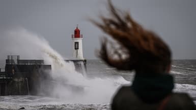 Une femme regarde les vagues s'écraser contre le phare à l'entrée du port pendant la tempête Nelson, aux Sables-d'Olonne, dans l'ouest de la France, le 28 mars 2024.