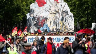 Gilets jaunes et syndicalistes à Paris le 27 avril, auprès d'une pancarte reprenant "La liberté guidant le peuple", d'Eugène Delacroix.
