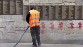 Un employé nettoie des tags de "mains rouges" sur le Mur des Justes du Mémorial de la Shoah à Paris, le 14 mai 2024.