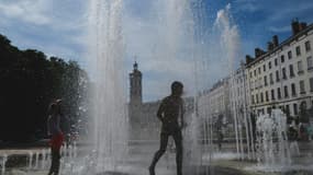 Des enfants se rafraîchissent dans une fontaine pendant une vague de chaleur, le 18 mai 2022 à Lyon