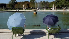 Deux personnes se protègent du soleil avec un parapluie durant une vague de chaleur tardive, au jardin des Tuileries à Paris, le 10 septembre 2023.