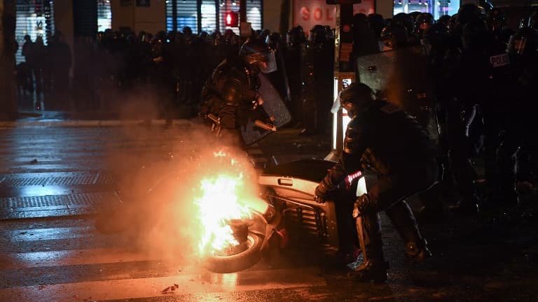 Des forces de l'ordre déplacent une carcasse de scooter enflammée sur la place de la République à Paris, le 26 janvier 2019. 