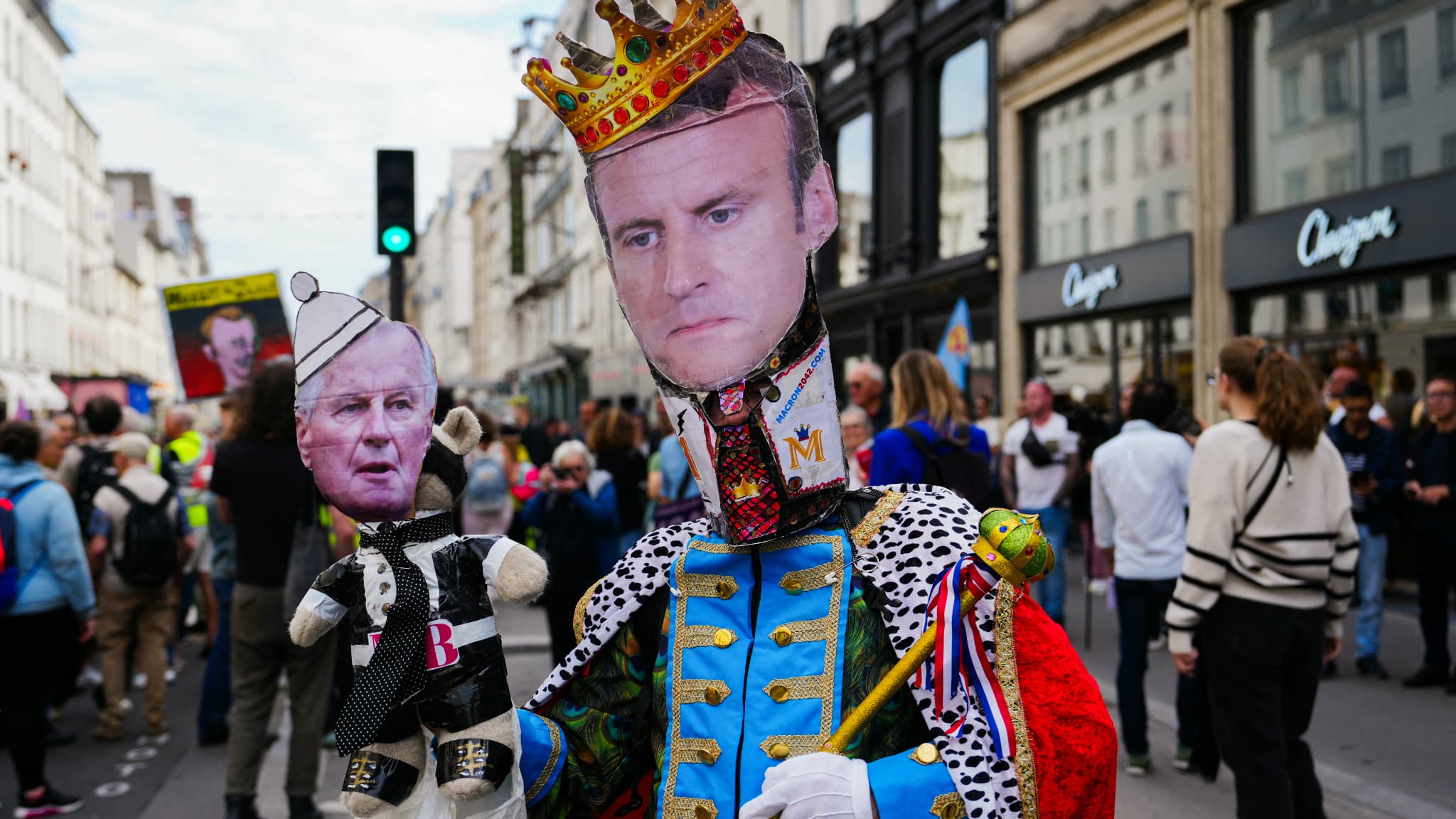 Emmanuel Macron en monarque tenant dans sa main une marionnette de Michel Barnier. Manifestation à Paris ce samedi 21 septembre 2024