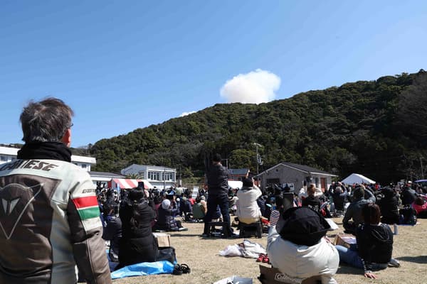 Des visiteurs regardent la fumée s'élever derrière une colline après l'explosion au décollage d'une petite fusée de la société Space One, basée à Tokyo, sur le site du Spaceport Kii à Kushimoto, dans la préfecture de Wakayama, le 13 mars 2024.