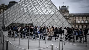 Des touristes devant la pyramide du Louvre