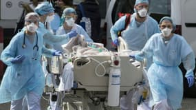 Des soignants entourent un malade lors d'un transfert vers l'hôpital Emile Muller à Mulhouse le 22 mars 2020
