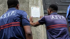 Des agents municipaux placardent des affichettes d'interdiction de circulation à venir, dans le bidonville de Majicavo à Mayotte, le 21 avril 2023