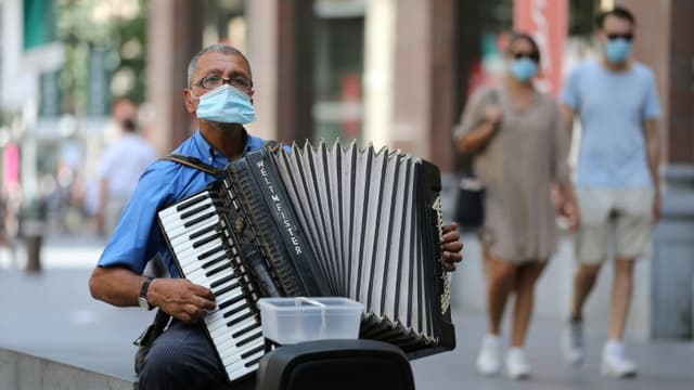Un joueur d'accordéon porte un masque dans une rue d'Antwerp, en Belgique, le 6 août 2020.