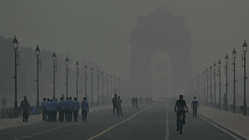 Des personnes marchent dans le brouillard à la Porte de l'Inde, à New Delhi, le 31 octobre 2023. L'ennemi est invisible et il n'y a pas de soldats, mais le nouveau "Green War Room" de la capitale indienne lutte contre la pollution de l'air qui réduit la durée de vie des habitants de plus d'une décennie.