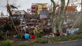 Des habitants assis devant leurs maisons détruites à Mamoudzou après le passage du cyclone Chido à Mayotte, le 17 décembre 2024