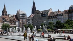 Des habitants et des touristes se rafraîchissent à la fontaine de la place Kléber à Strasbourg.