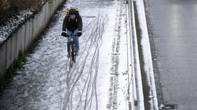 Un homme fait du vélo dans une rue enneigée de Mulhouse, le 8 janvier 2024.