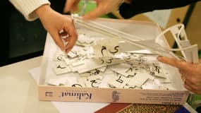 Des personnes manipulent les pièces d'un puzzle en arabe, le 19 janvier 2006 à Paris, sur un stand de la 24e édition du salon Expolangues. 