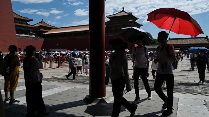 Des passants se protègent de la chaleur à Pékin, le 9 juillet 2023.