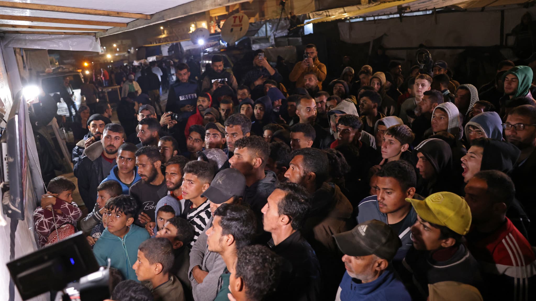 Des personnes regardent la retransmission en direct d'une conférence de presse du Premier ministre du Qatar, Cheikh Mohammed bin Abdulrahman bin Jassim Al-Thani, dans une rue de Khan Yunis, dans le sud de la bande de Gaza, le 15 janvier 2025. Des personnes regardent la retransmission en direct d'une conférence de presse du Premier ministre du Qatar, Cheikh Mohammed bin Abdulrahman bin Jassim Al-Thani, dans une rue de Khan Yunis, dans le sud de la bande de Gaza, le 15 janvier 2025.