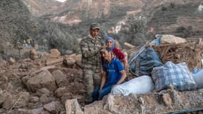 Un soldat marocain, un homme et une femmes au milieu des des décombres dans la zone montagneuse de Tizi N'Test, dans la province de Taroudant, l'une des plus dévastées du Maroc, le 11 septembre 2023.