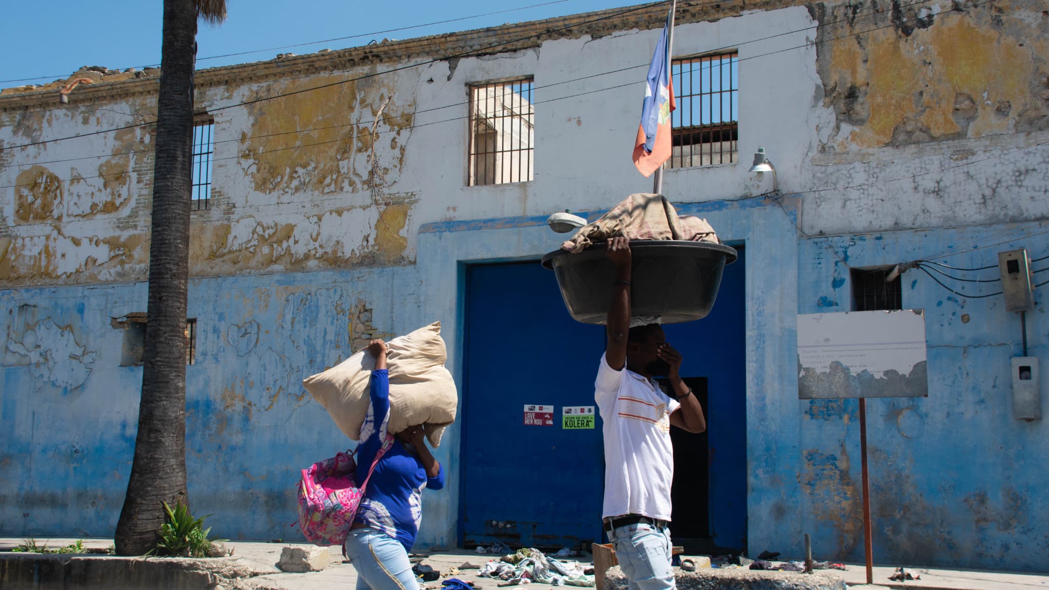 Des personnes marchent les mains sur le visage pour se protéger de la puanteur des corps en décomposition alors qu'elles passent devant le pénitencier national de Port-au-Prince, Haïti, 4 mars 2024.
