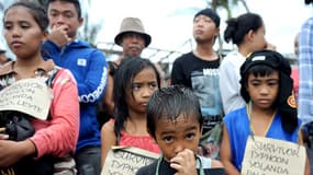 Enfants rescapés du typhon Haiyan (appelé localement "Yolanda"), portant une pancarte afin d'être évacués en priorité.