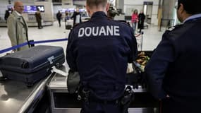 Des douaniers inspectent les bagages de passagers à l'aéroport de Roissy-Charles-de-Gaulle, au nord de Paris, le 21 mars 2025 (image d'illustration).