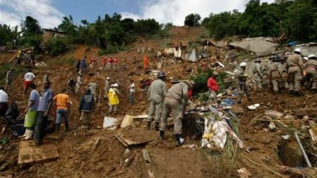 Pompiers à l'oeuvre après un glissement de terrain dans le bidonville de Morro dos Prazeres, à Rio de Janeiro. Les secouristes tentaient désespérément, mercredi, de dégager de la boue et des débris les dizaines de personnes toujours portées disparues aprè