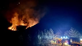 L'incendie dans une forêt et des véhicules de sapeurs-pompiers au cours de l'intervention, dans la nuit de vendredi 12 à samedi 13 juillet, vers Vergons, dans les Alpes-de-Haute-Provence.