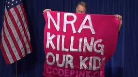 Un manifestant tenant une banderole "la NRA tue nos enfants"