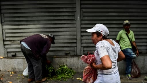 Des Vénézuéliens récupèrent de la nourriture après le pillage d'un marché à Caracas, le 10 mars 2019
