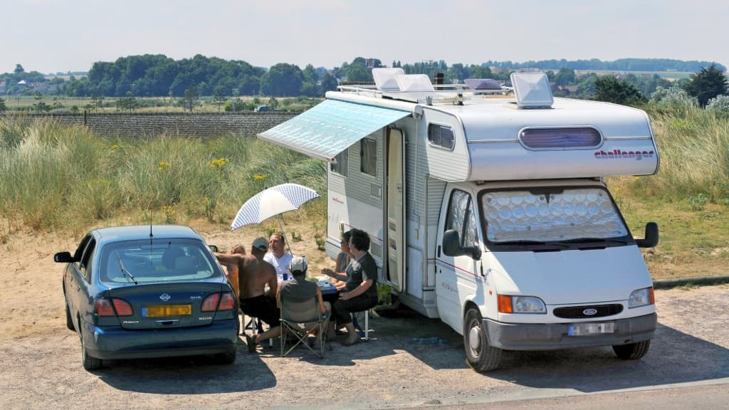 Des touristes en train de déjeuner devant leur camping-car près de La Graye-sur-Mer en Normandie.