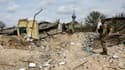 Un militaire ukrainien regarde un cratère creusé par des bombardements près d'une maison détruite dans le village de Yatskivka, dans l'est de l'Ukraine le 16 avril 2022 (illustration)
